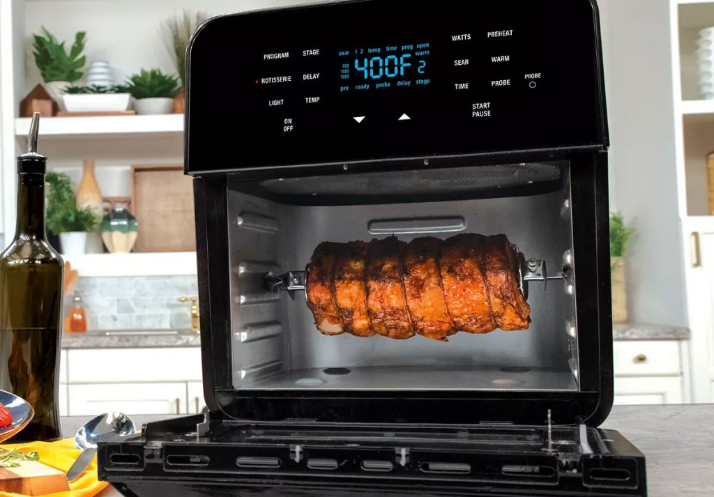 black NuWave air fryer oven on kitchen counter with rotisserie meat inside