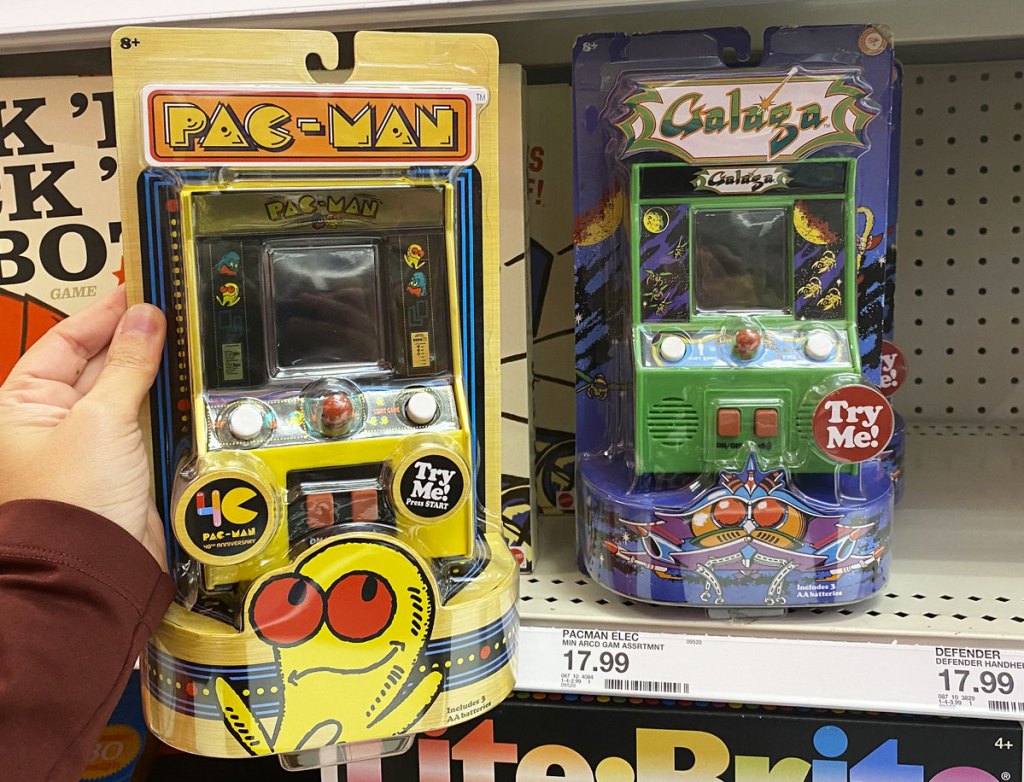 person holding up a yellow pac-man mini arcade machine game