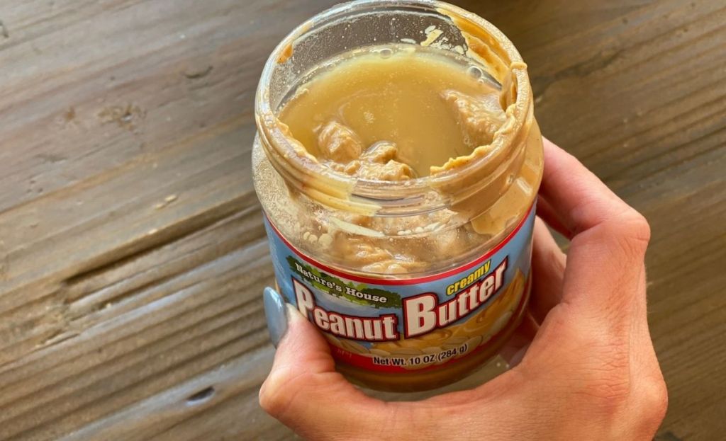 A hand holding a jar of peanut butter