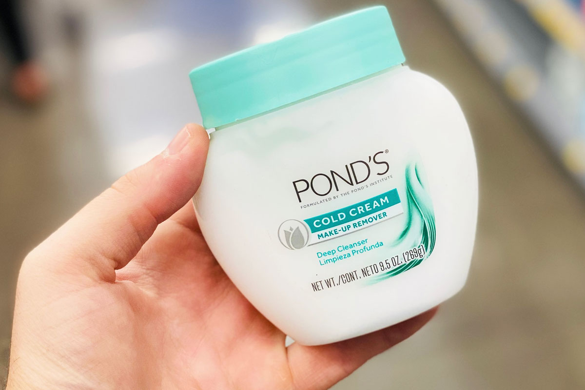 person holding white and green jar of Pond's Cold Cream Makeup Remover