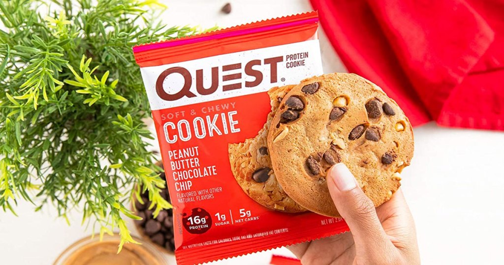person holding up quest peanut butter chocolate chip cookie and red wrapper