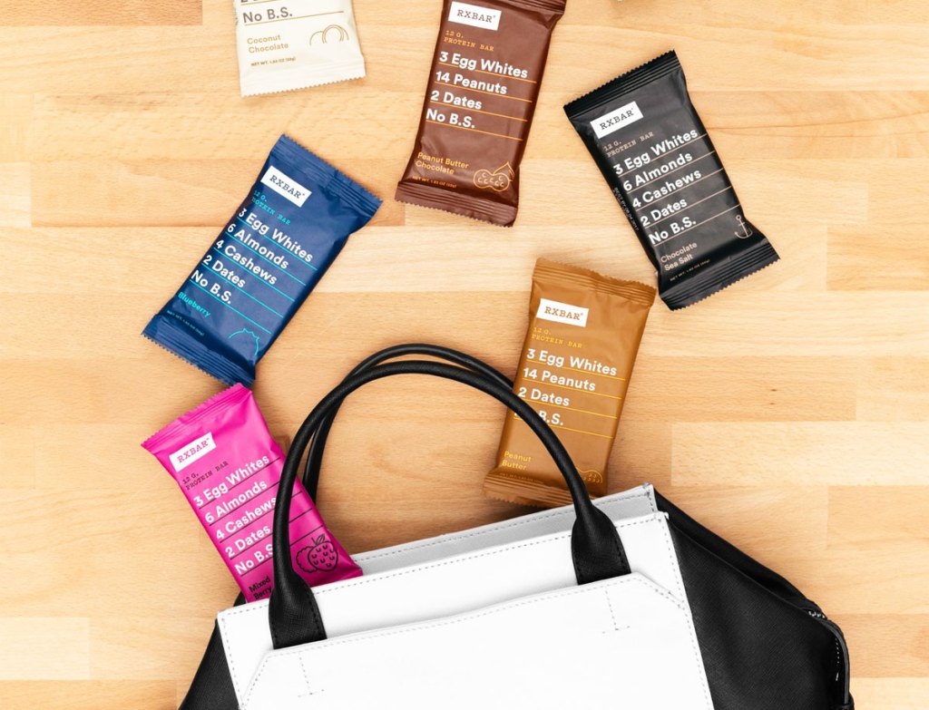 various flavors of rxbar protein bars coming out of a black and white purse on hardwood floor