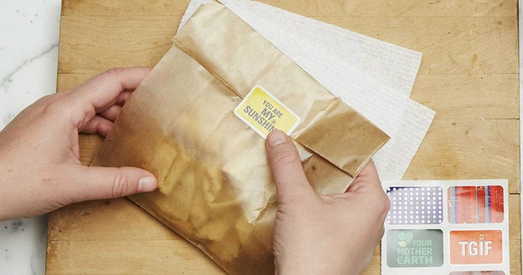 Hands holding a wax paper sandwich bag, and sealing it with a sticker