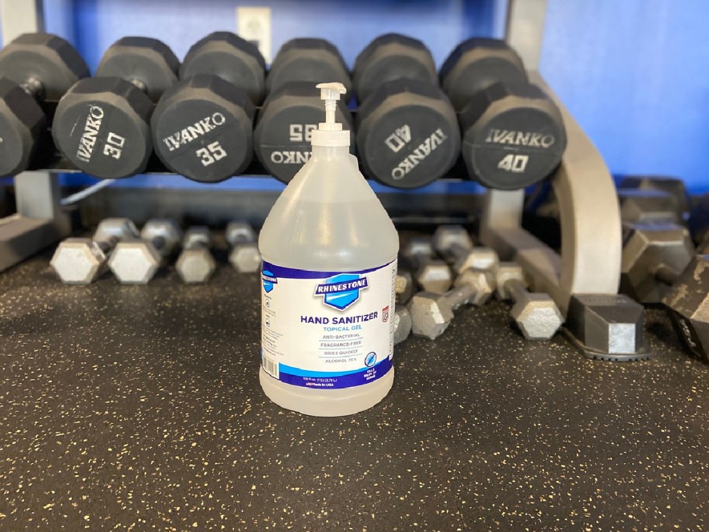 Rhinestone Hand Sanitizer in gallon jug on floor with iron weights