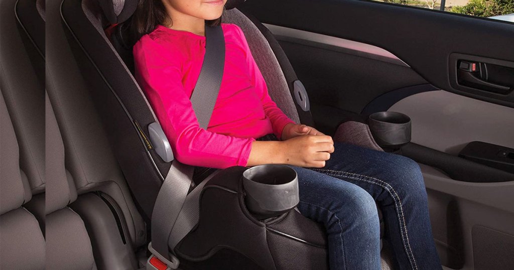 girl in pink shirt and jeans sitting in grey and black car seat in car