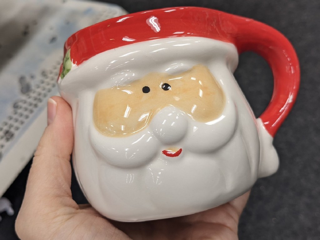 hand holding mug shaped like Santa