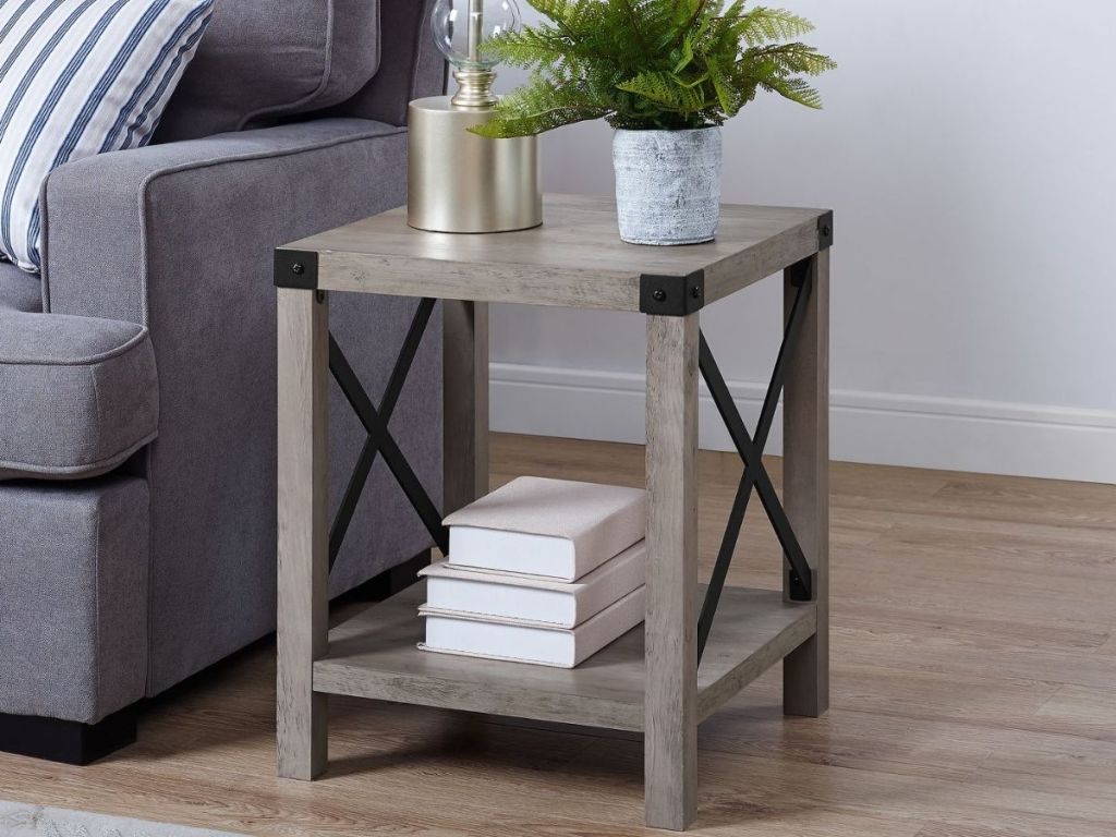 gray farmhouse side table with plant and light on table and books underneath