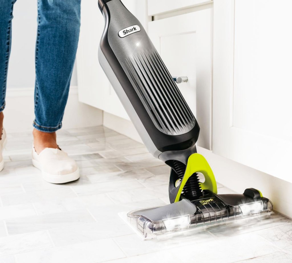 person using a black and grey shark vacmop on white tile floors