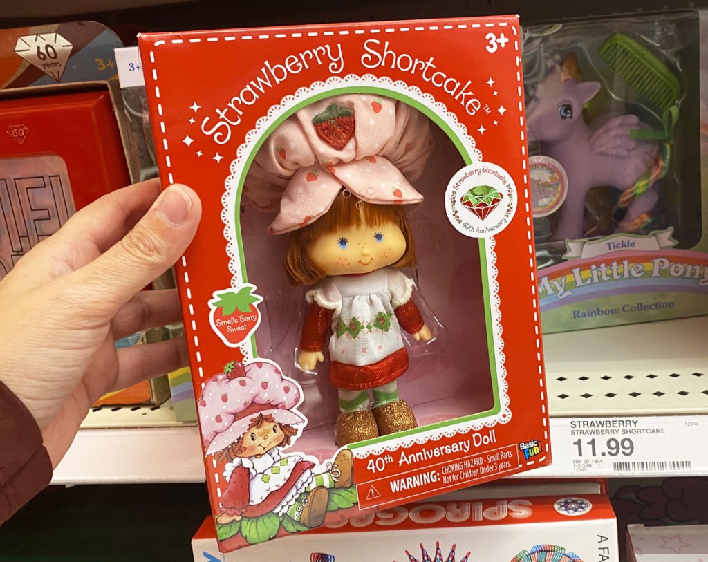 person holding up strawberry shortcake doll in a red box