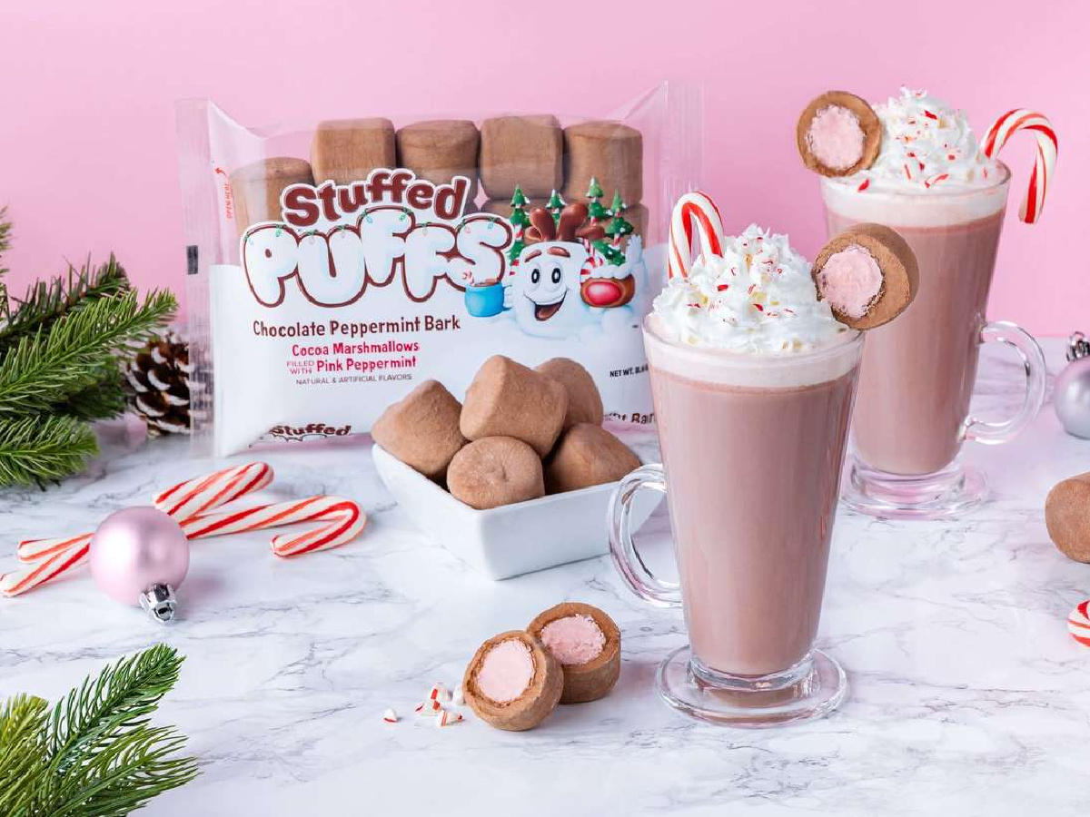 bag of chocolate peppermint marshmallows, two milkshakes, candy canes, pine cones marshmallows, and ornaments on white marble counter