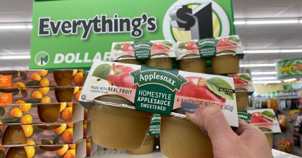 A hand grabbing a pack of applesauce off a store shelf