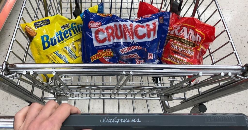 Shopping cart with three bags of halloween candy in the front basket
