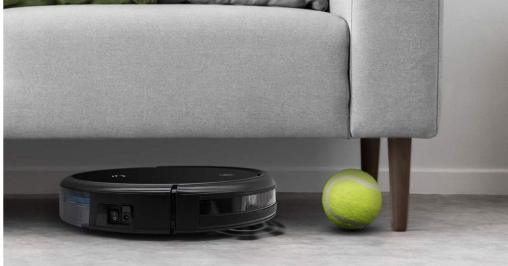 black robot vacuum under gray couch