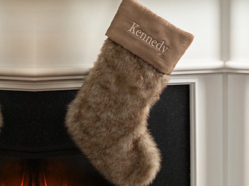 faux fur personalized stocking hanging on a fireplace mantle