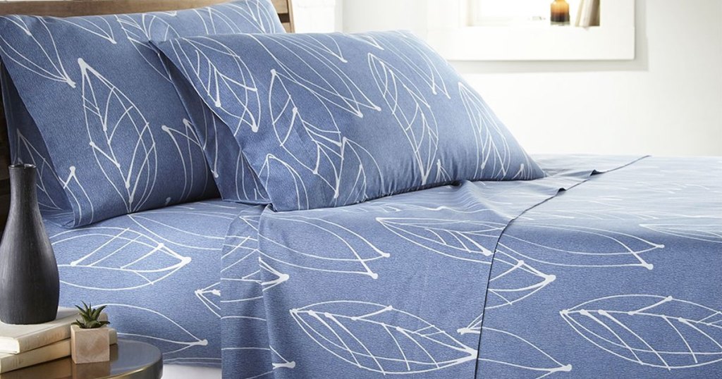 blue sheets with white leaf print sign on bed with matching pillow shams