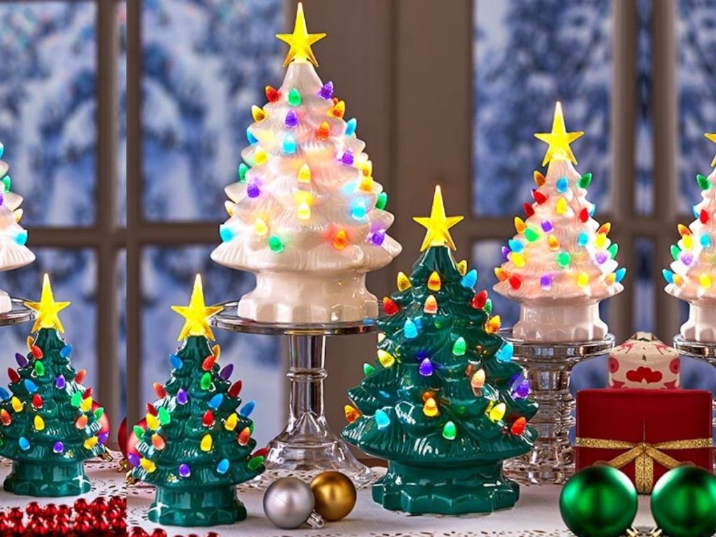 white and green small and medium sized ceramic Christmas trees on table with ornaments scattered