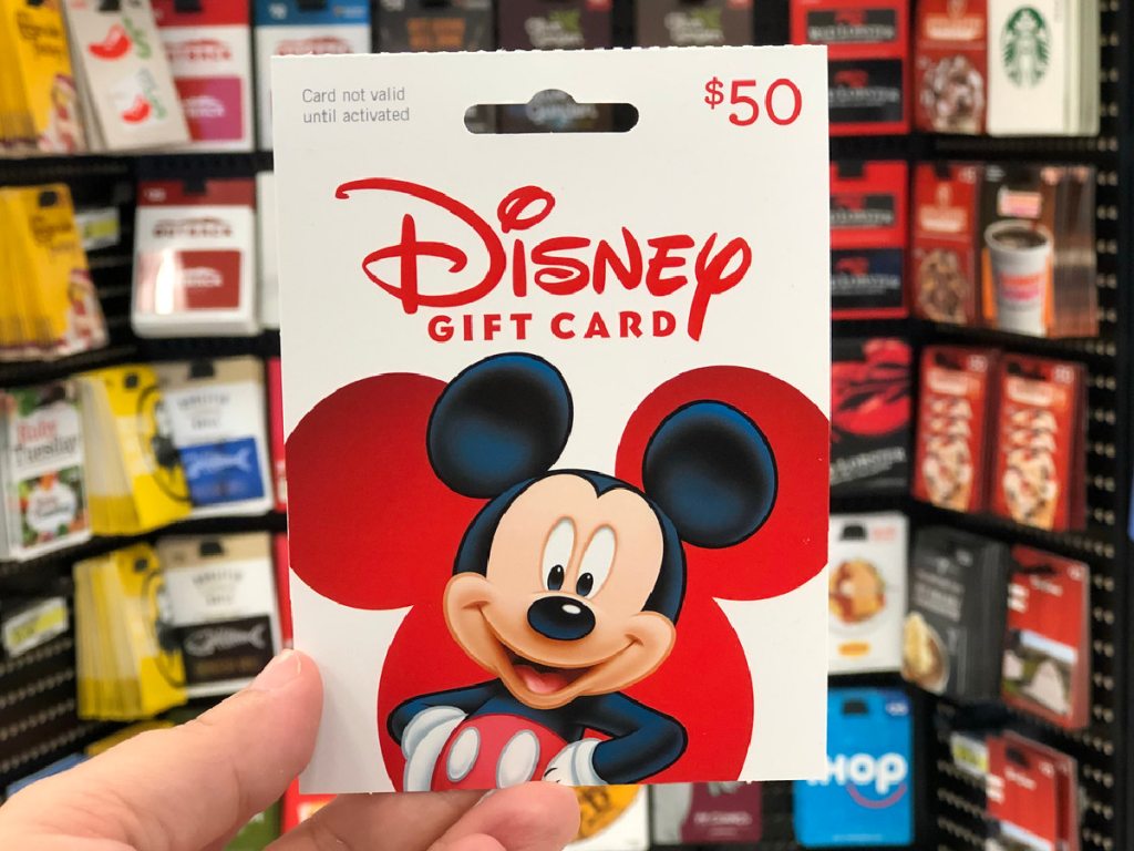 hand holding up Disney gift card by store display
