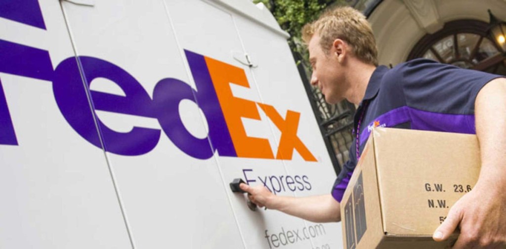 man putting box on FedEx truck