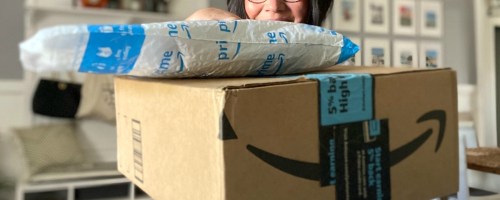 Woman holding packages with Amazon logo