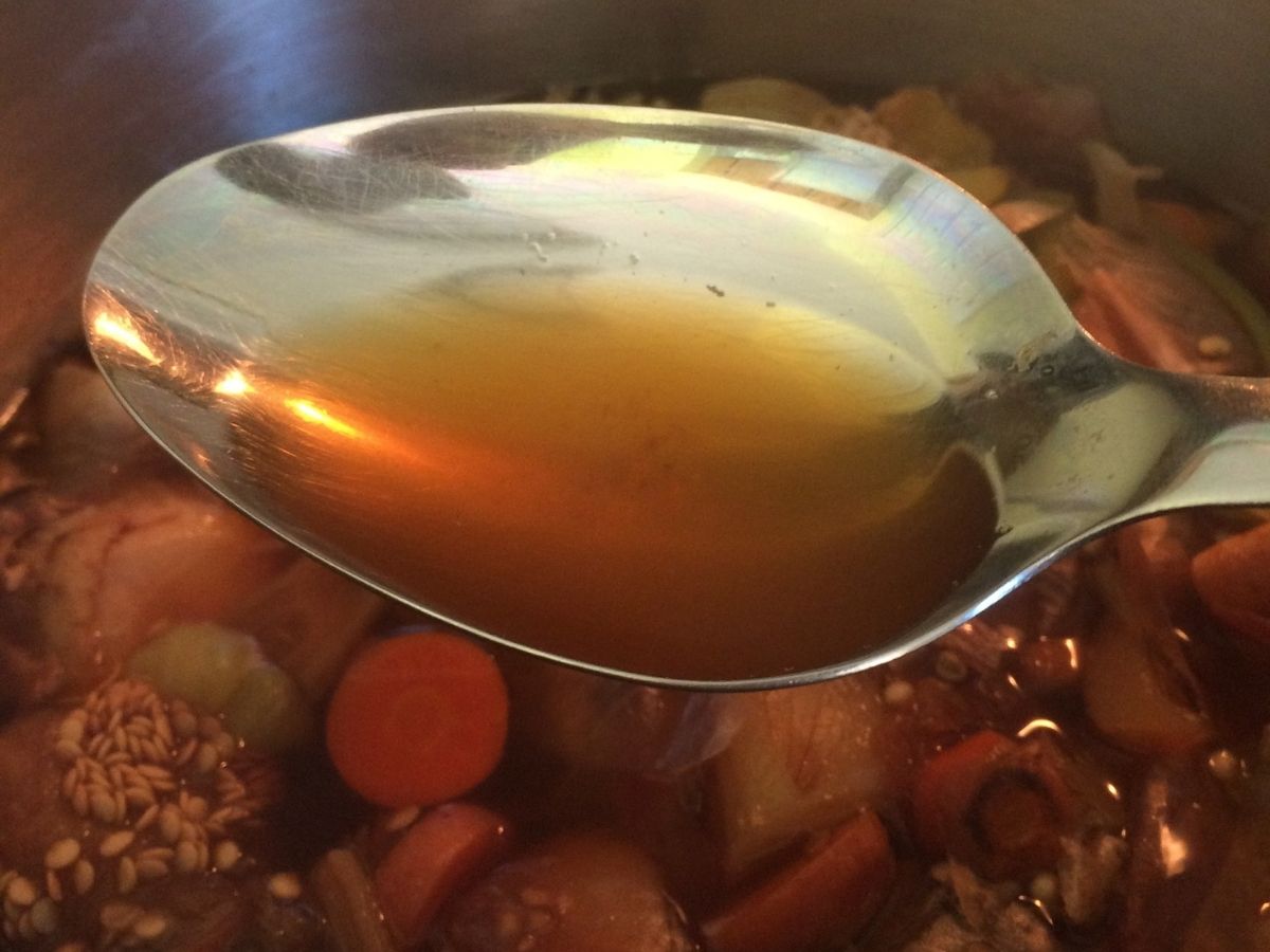 spoon with broth and veggie stock in background