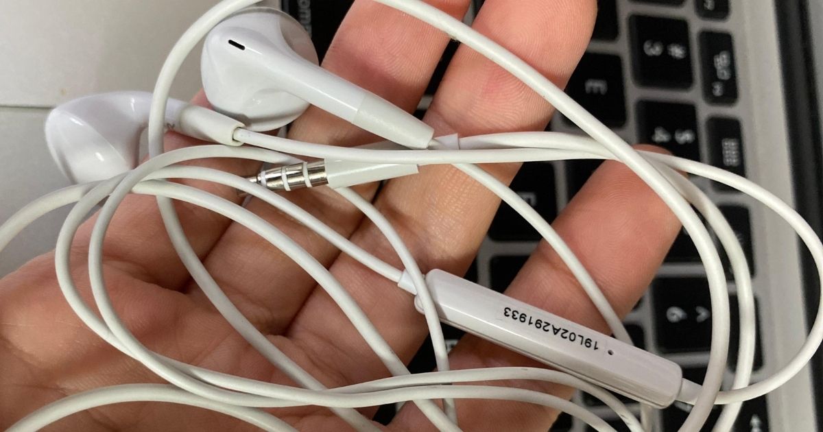 hands holding wired Insignia while earbuds