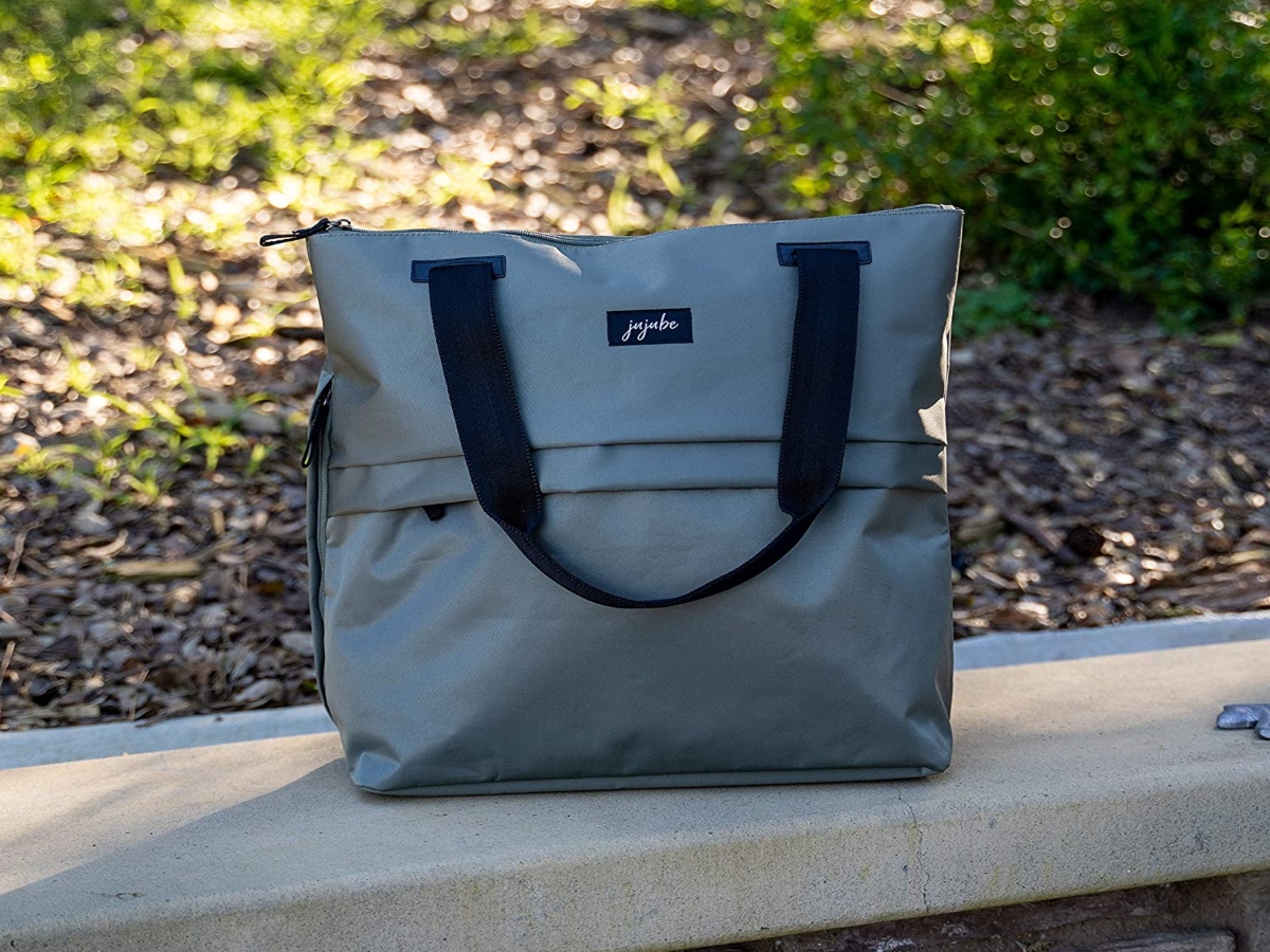 grey tote bag on a cement wall, outside. It has dark straps
