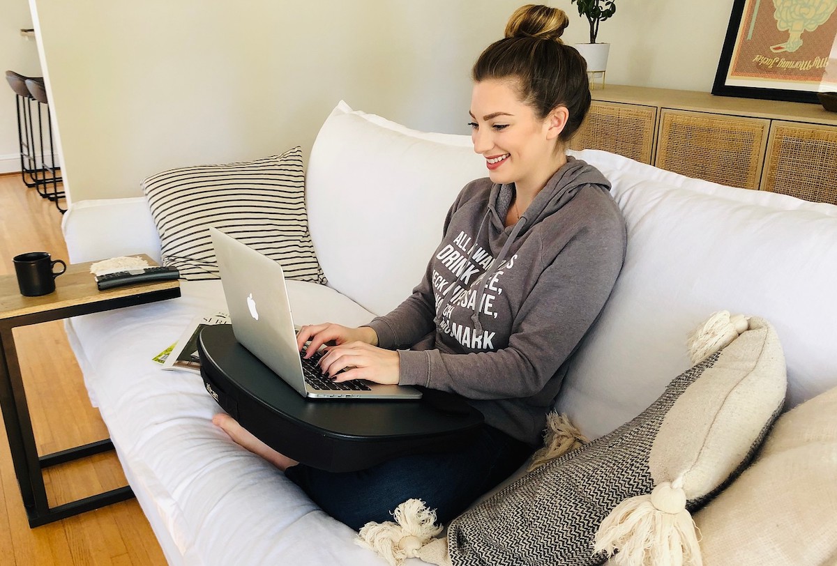 woman typing on laptop while sitting on white couch