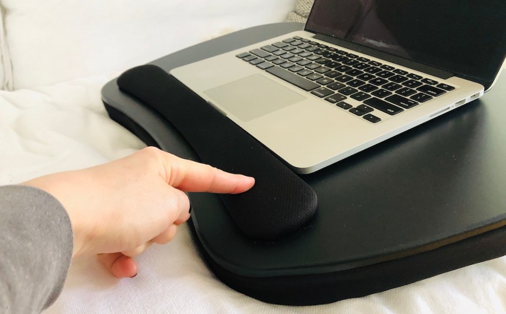 persons finger poking black foam wrist guard next to laptop