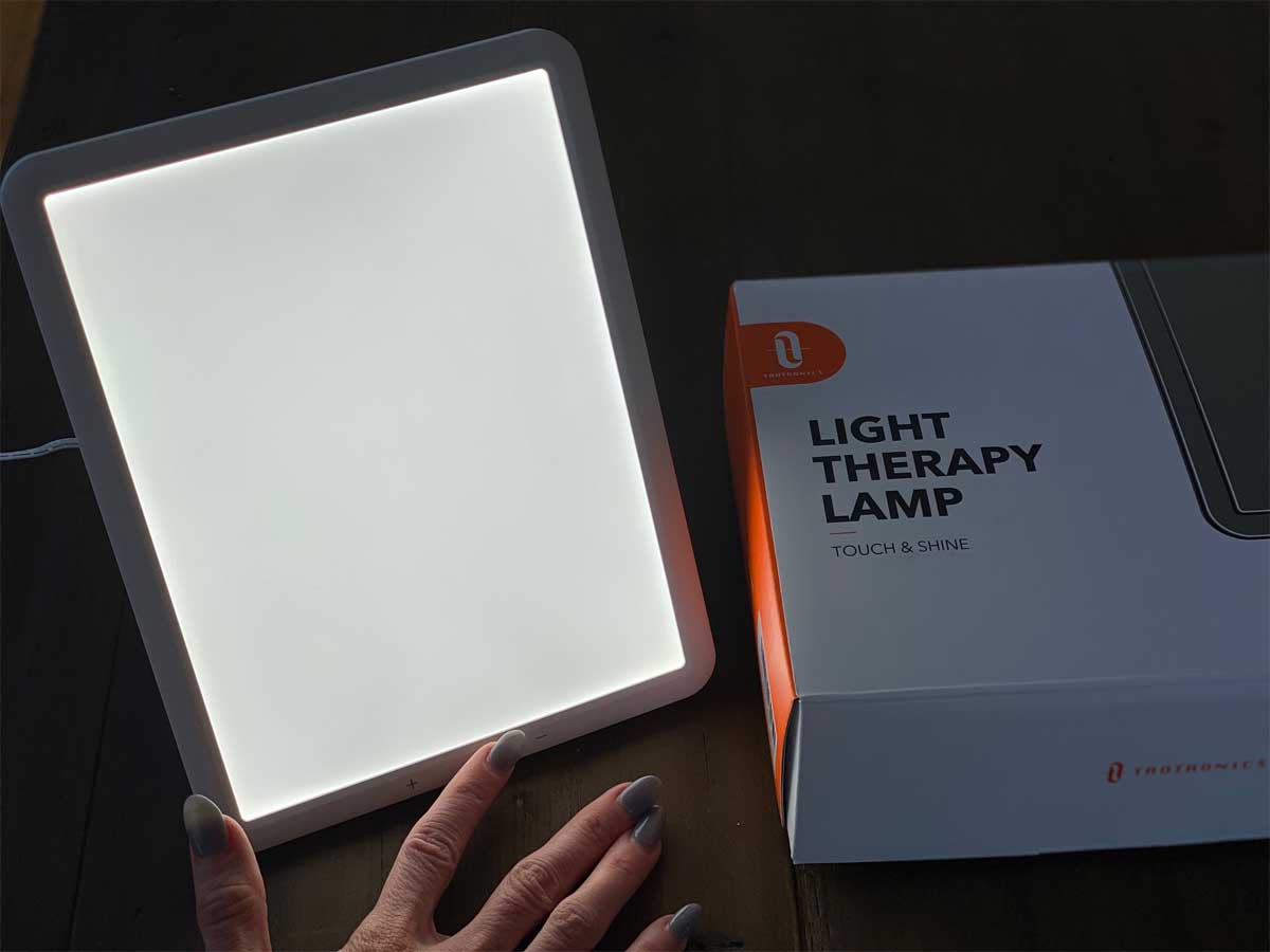 hand showing touch button on illuminated light therapy lamp