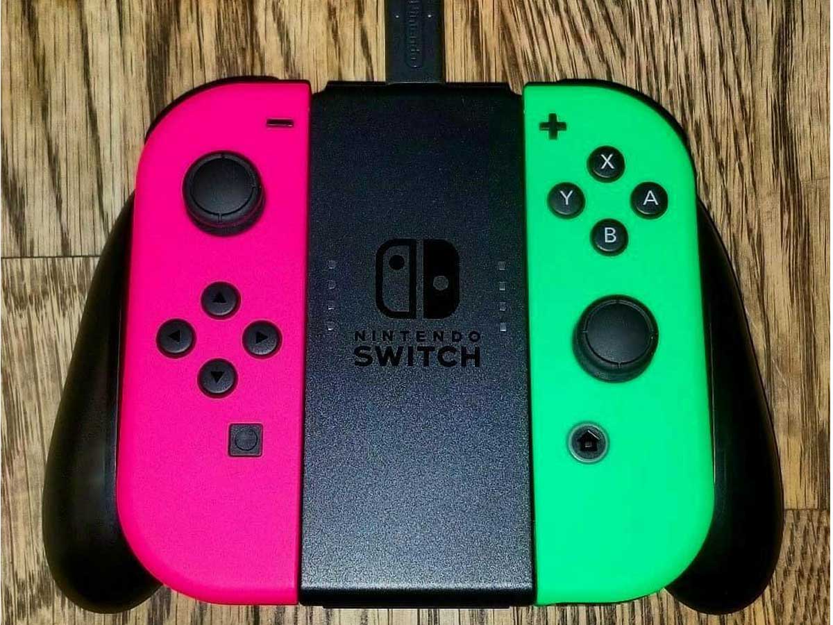 nintendo switch on a table with green and pink joy cons