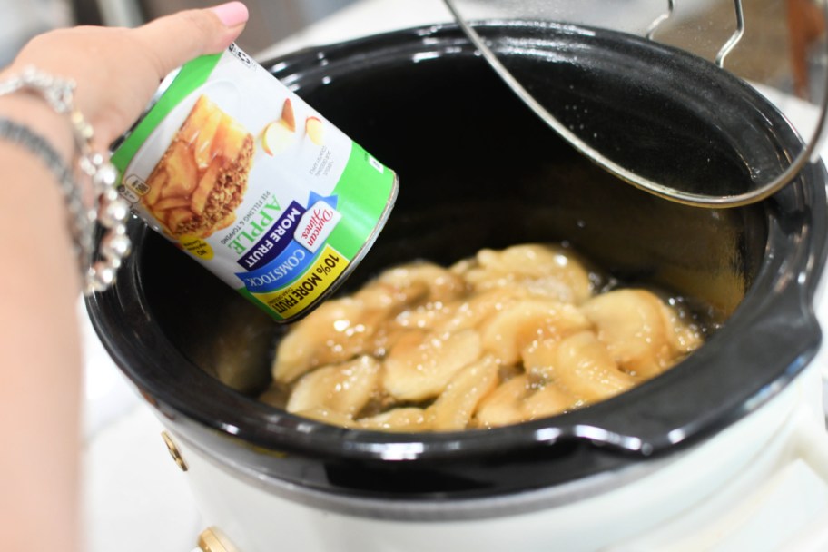 pouring can of apple pie filling into a slow cooker 