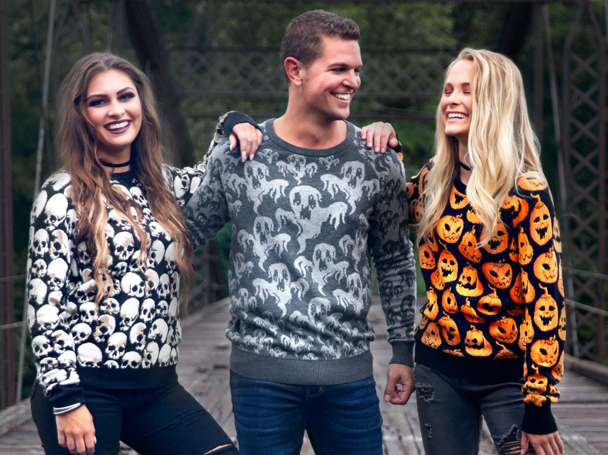 man and two women wearing Halloween sweaters