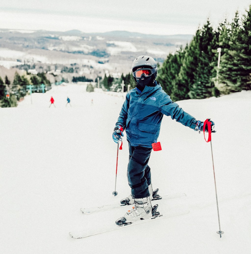 boy with skiis standing on mountain