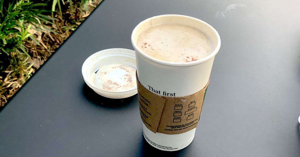starbucks snickerdoodle latte with lid off sitting on black table outside