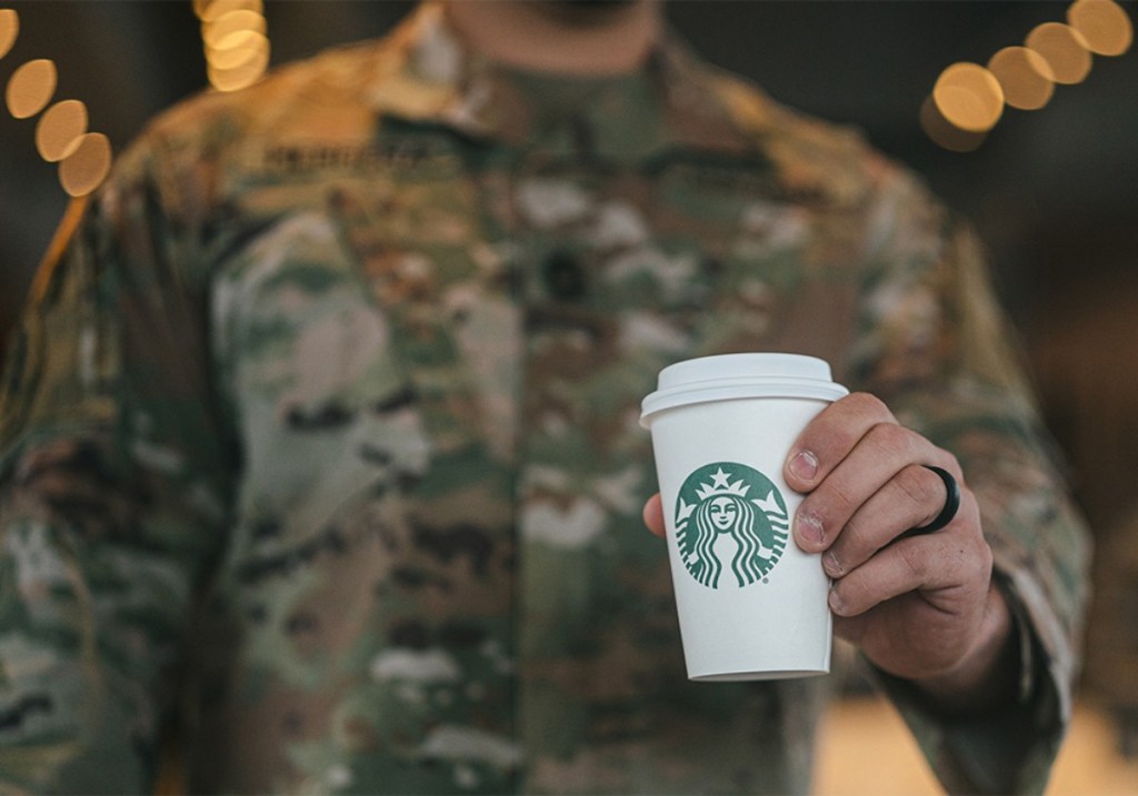 US service person in uniform holding a Starbucks cup