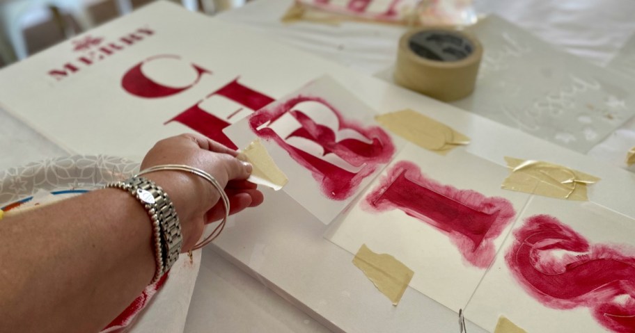 stenciling merry christmas to a sign