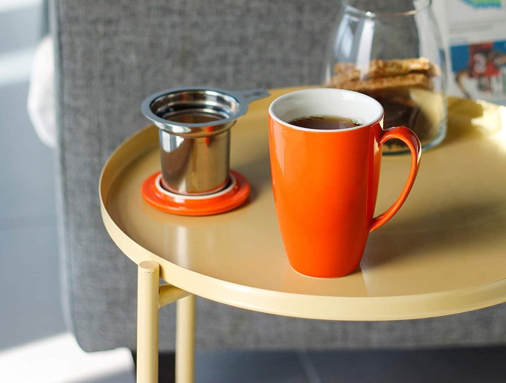 sweese mug in orange color with lid on coffee table