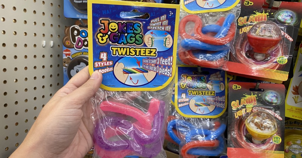 hand holding package of toy noodles in front of store display