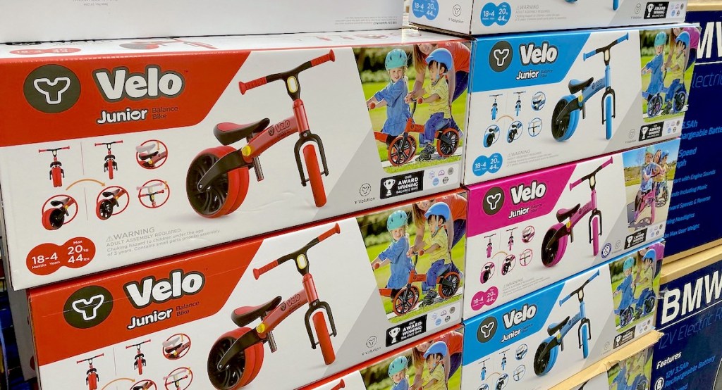 red blue pink toddler balance bikes in boxes staked at store