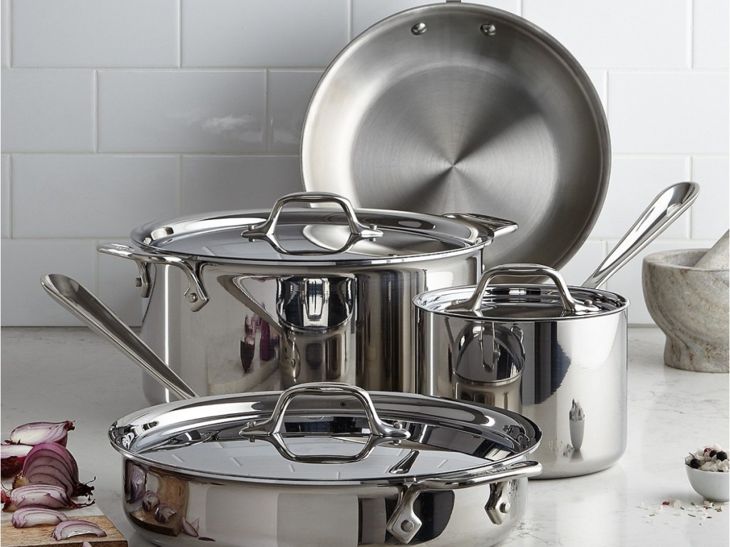stainless steel pots and pans and cutting board with onions on counter