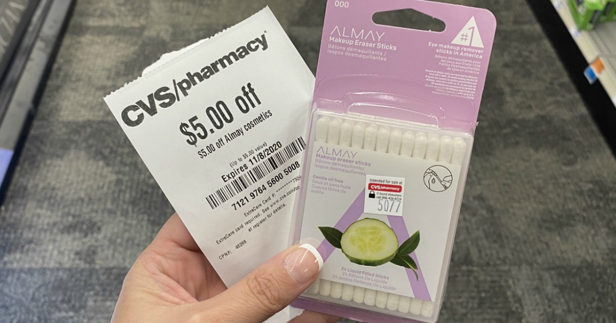 hand holding Almay Makeup Eraser Sticks and CVS coupon in store