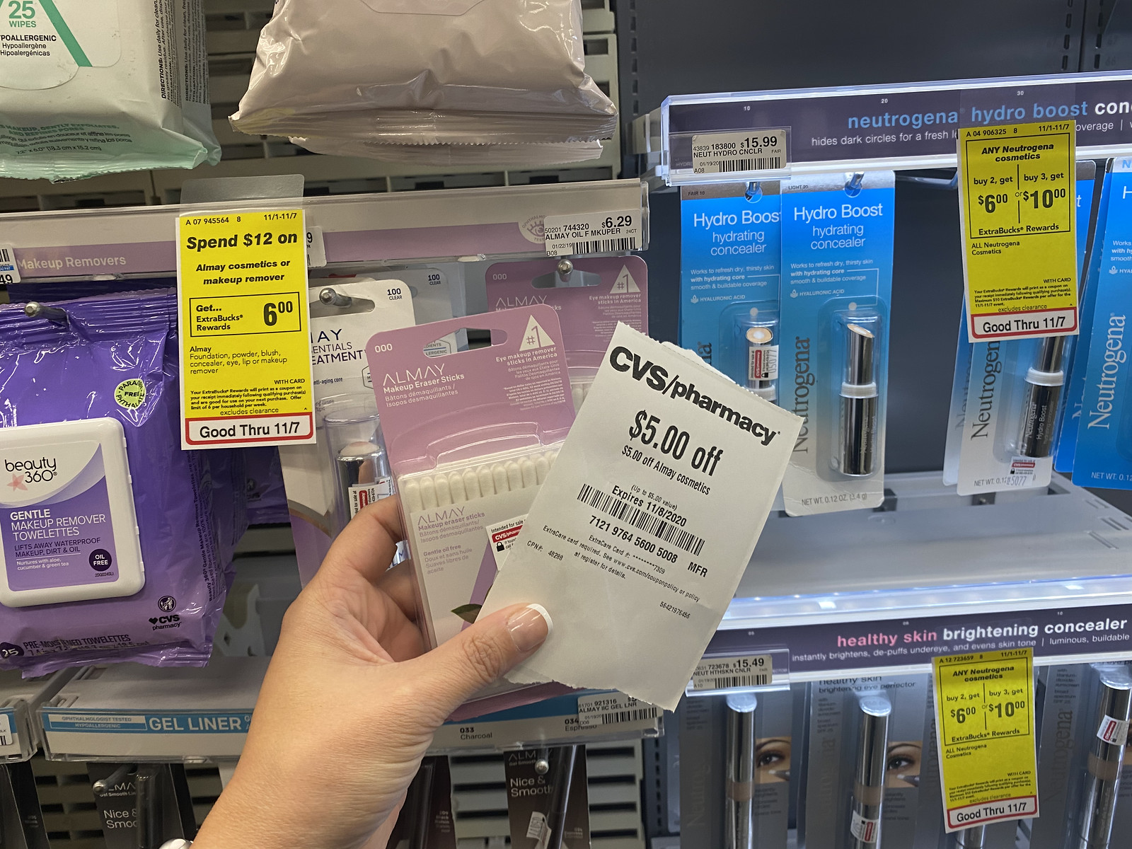 Hand holding up Almay Remover Sticks and coupon in CVS store
