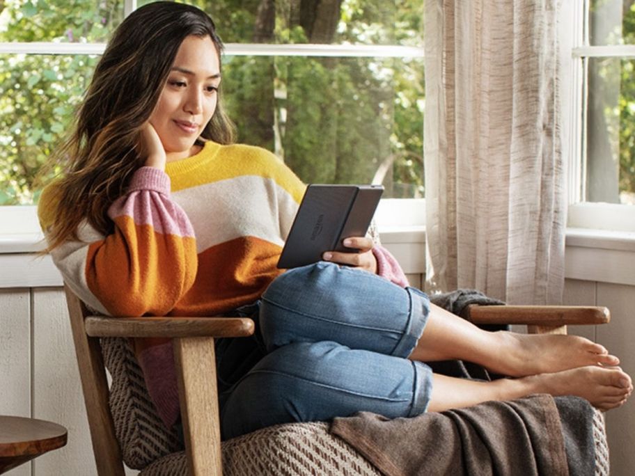 woman sitting in chair reading amazon kindle oasis