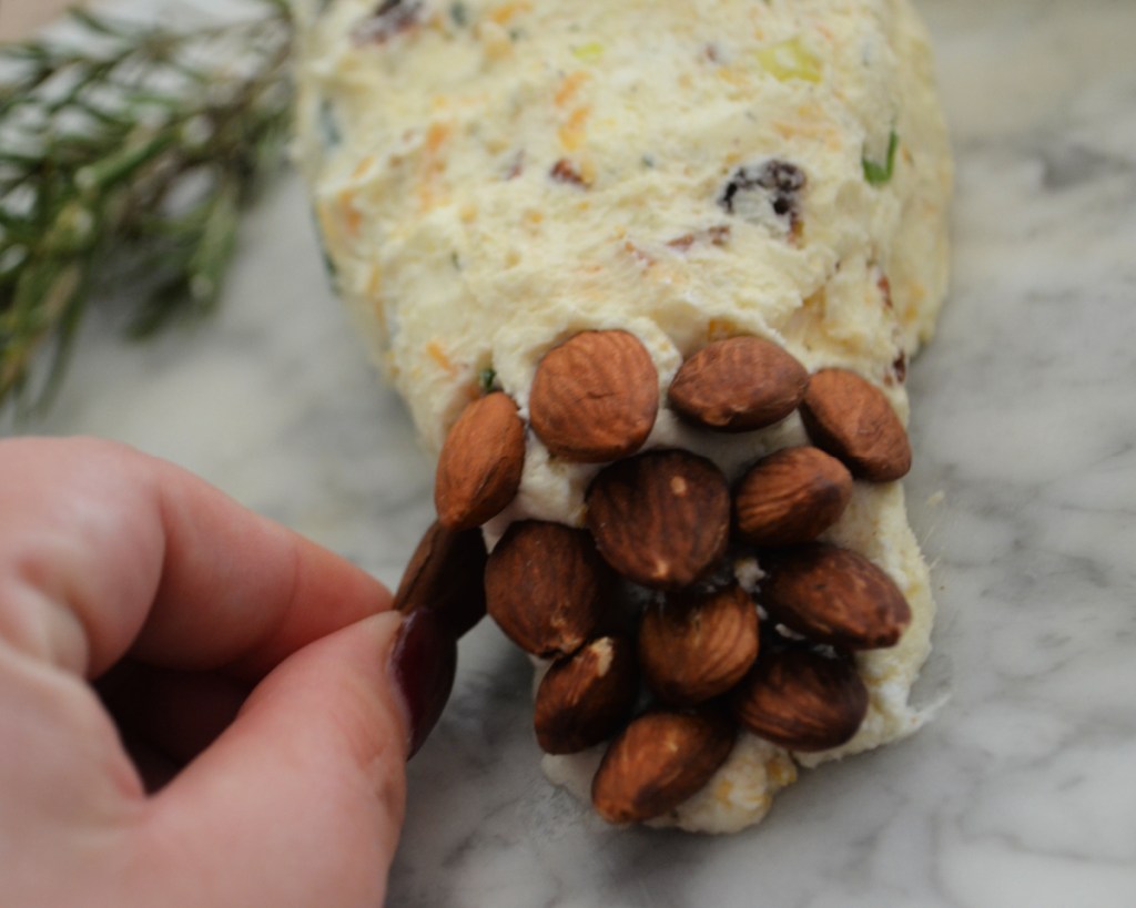 applying almonds to a pine cone cheeseball