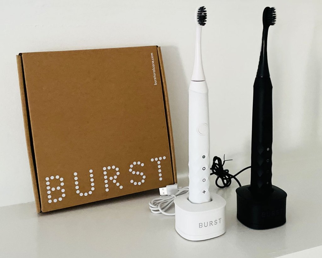 two white and black electric toothbrushes on white table near brown BURST shipping box