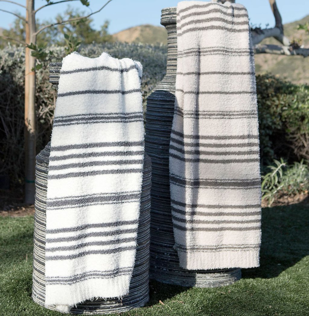 two stiped barefoot dreams blankets draped on large decorative planters outside
