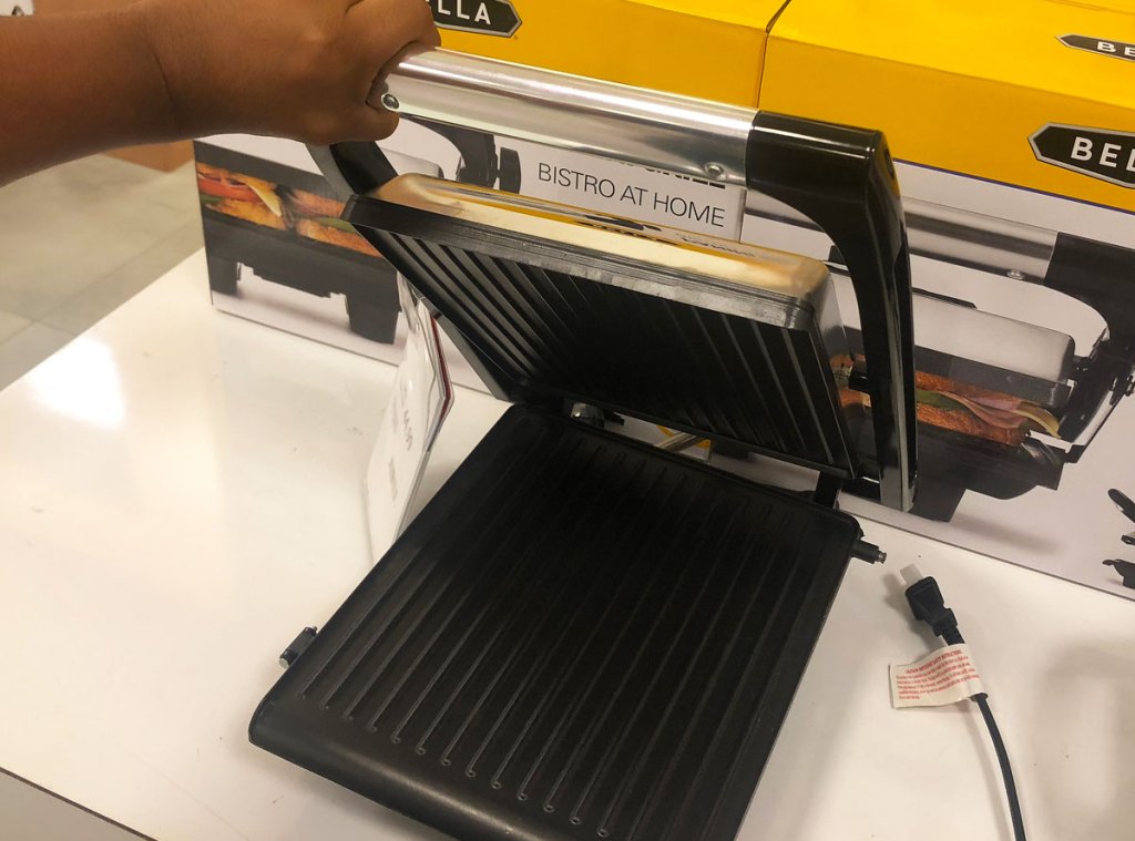 person holding up the lid to a panini press grill on display at macy's