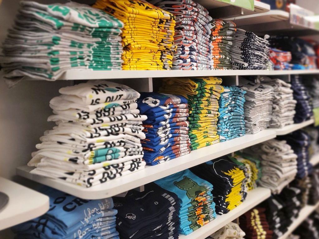display of boys graphic shirts folded on white shelves