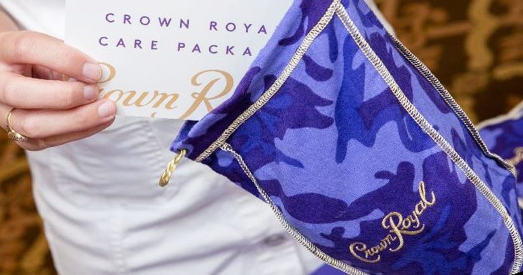 person adding a note into a purple camo print crown royal bag care package