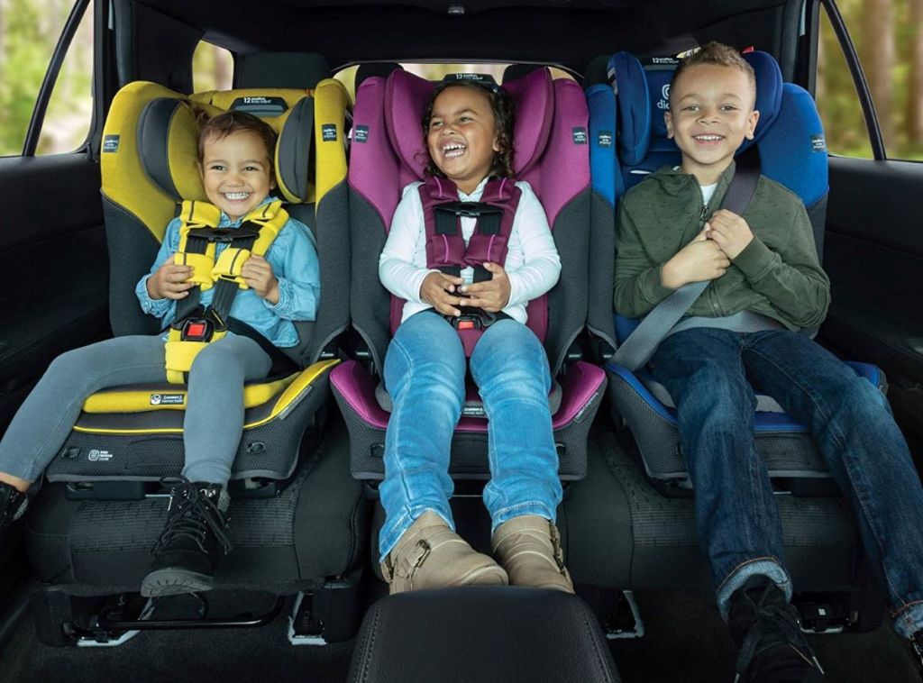 three kids in car seats in a car